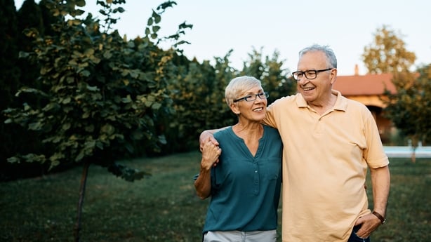 Happy senior couple enjoying while walking embraced in their backyard