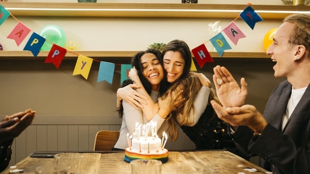 a group of women hugging in front of a cake