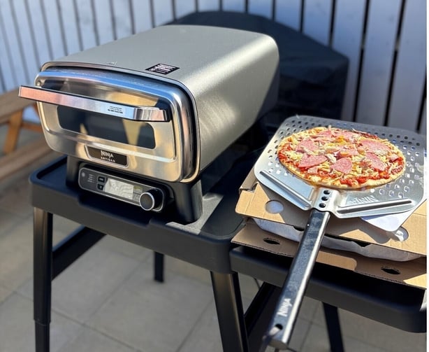 a pizza cooking machine and a pizza on a pan