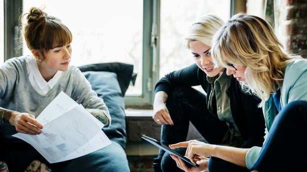 Three businesswomen sitting on large Pillows in an office and talking during an informal meeting