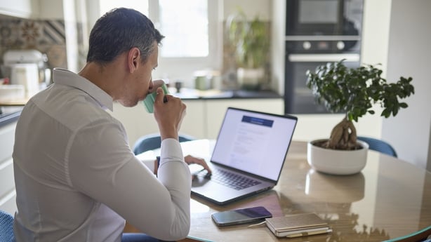 Man sitting at home in front of his laptop browsing job listings. The image represents job search, remote work, and digital communication.