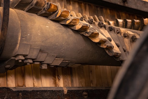 a man creating beetled linen on a large wooden press