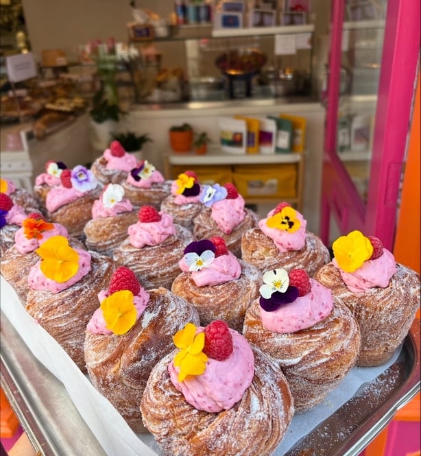 a tray of pastries with pink frosting and flowers
