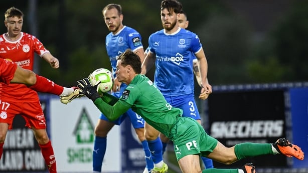 23 June 2025; Waterford goalkeeper Stephen McMullan makes a save as he is challenged by the boot of Ellis Chapman of Shelbourne during the SSE Airtricity Men's Premier Division match between Waterford and Shelbourne at the Regional Sports Centre in Waterford. Photo by Piaras Ó Mídheach/Sportsfile