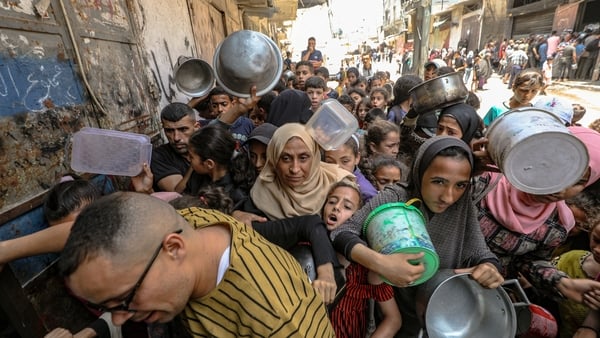 Women and children are seen trying to access food in Nuseirat Camp